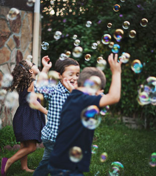 Children playing with bubbles floating around them